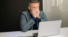 Man Sitting on Black Chair Covering His Face
