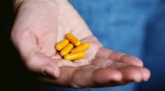 Person Holding Yellow Pills