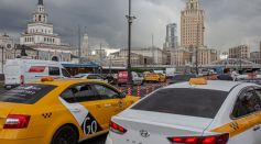 white and yellow taxi cab on road near city buildings during daytime